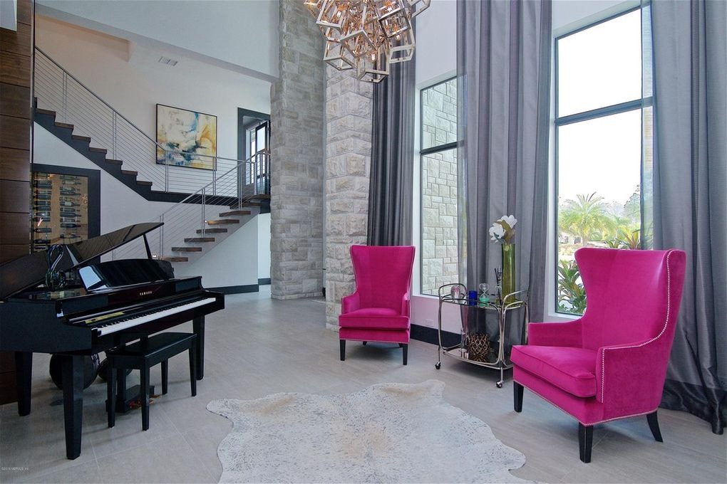 Accent wall idea - interior modern home with stone veneer accent wall and piano and pink chairs